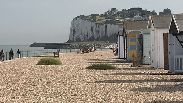 A pebble beach with a cliff in the background, a fence, and a row of small buildings. - 100 meters from the beach, Charming coastal period house. (Kingsdown Deal)