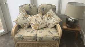 A wicker sofa with floral cushions, a lamp, and a window with blinds. - 100 meters from the beach, Charming coastal period house. (Kingsdown Deal)