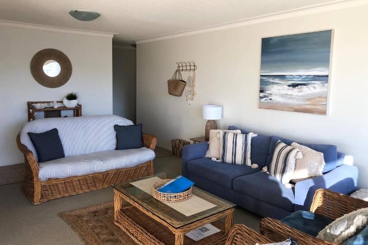 A living room with a wicker sofa, a blue sofa, and a coffee table.