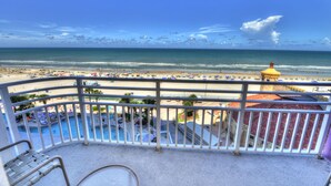 A balcony with a view of a beach and a pool area.