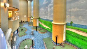 A miniature golf course with a view of the ocean and palm trees.