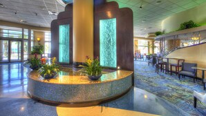 A lobby with a central water feature, seating area, and a staircase.