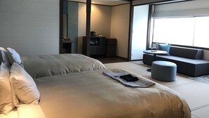 Una habitación de hotel moderna con una cama grande, un pequeño rincón de descanso y una kitchenette.