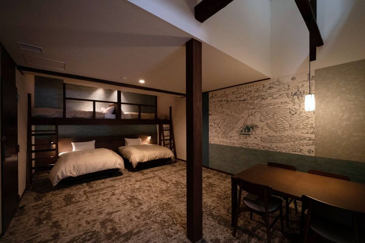 A room with bunk beds, a dining table, and a mural on the wall.