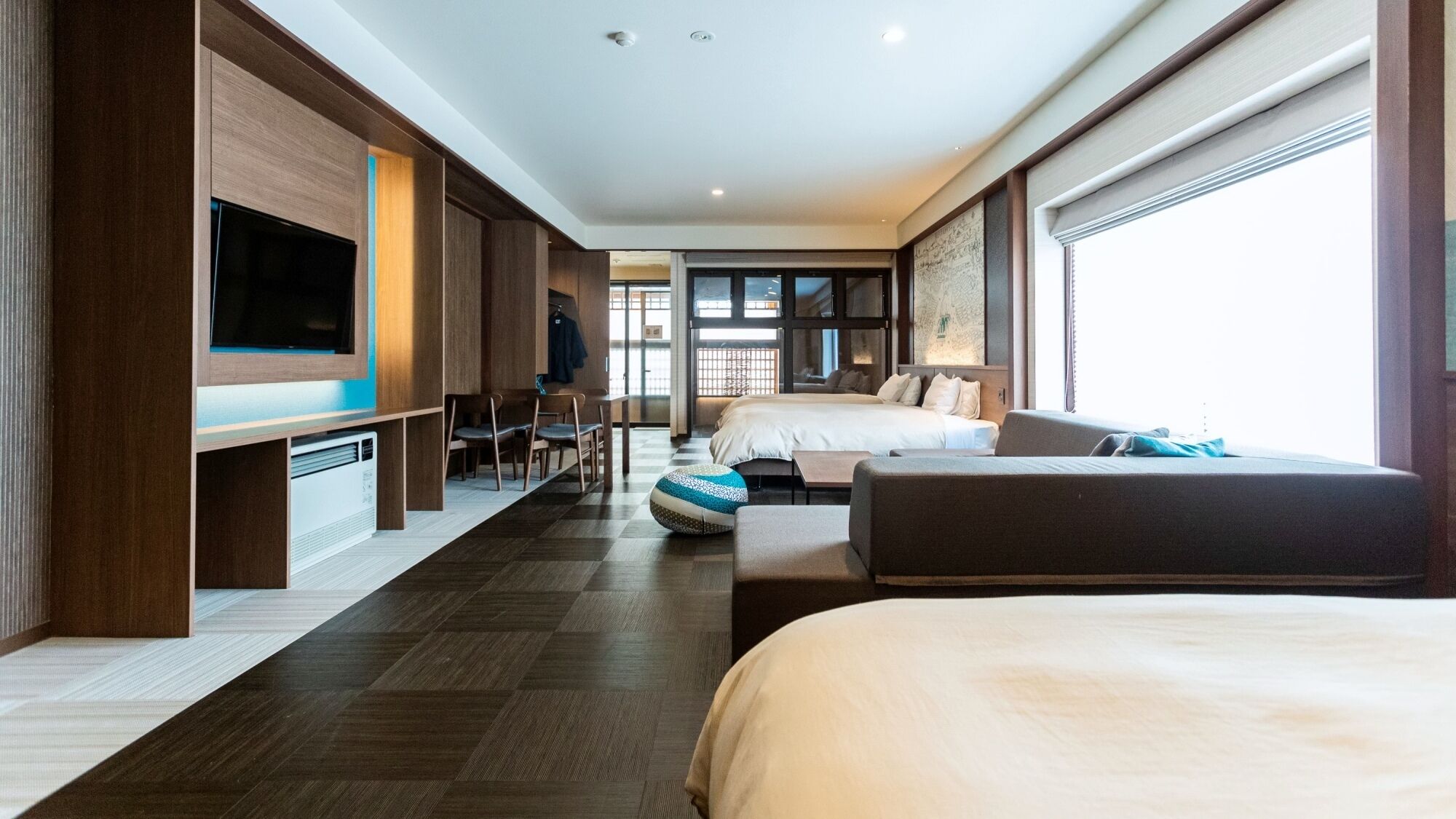 A modern hotel room with a large bed, a sofa, a TV, and a desk.