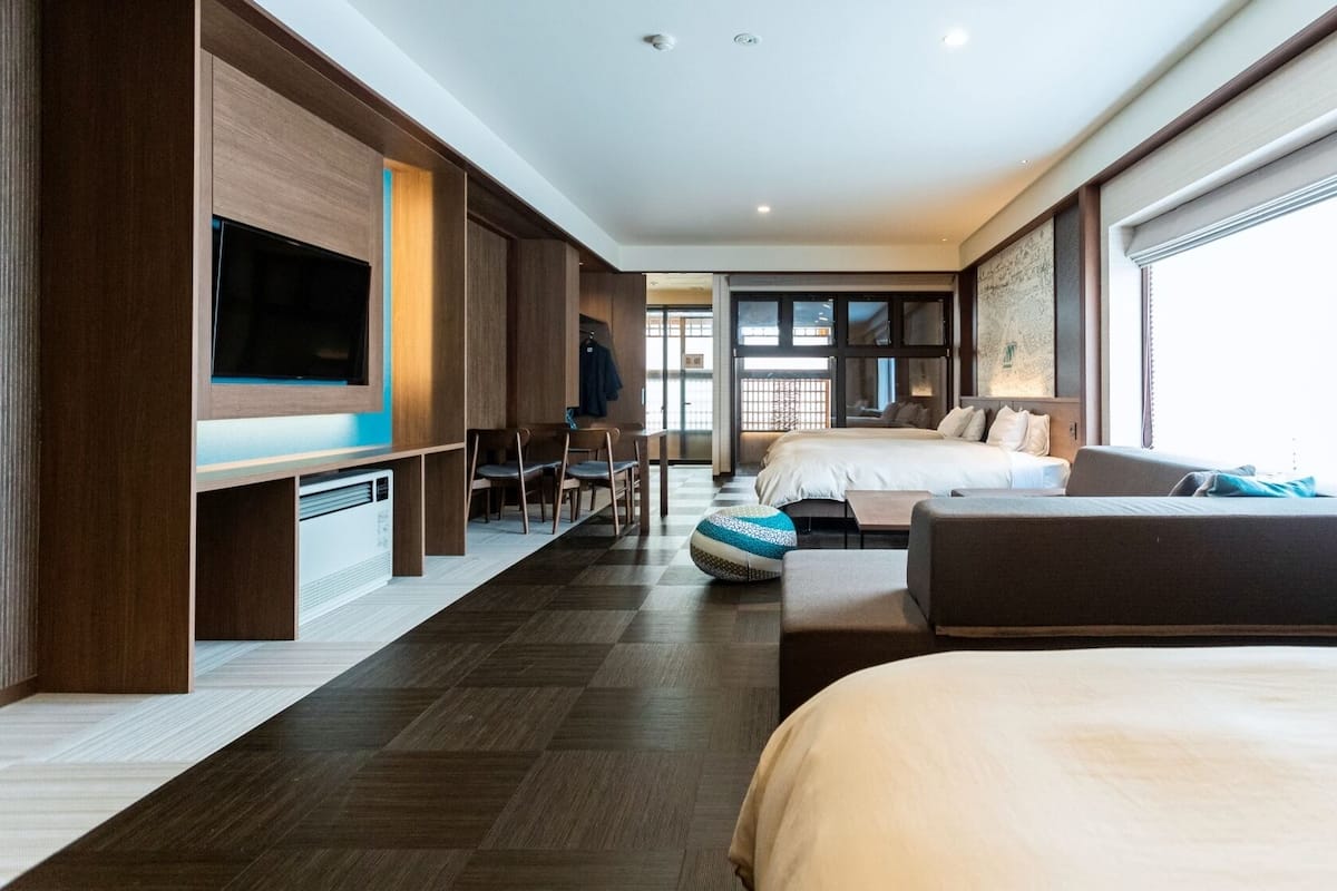 A modern hotel room with a large bed, a sofa, a TV, and a desk.