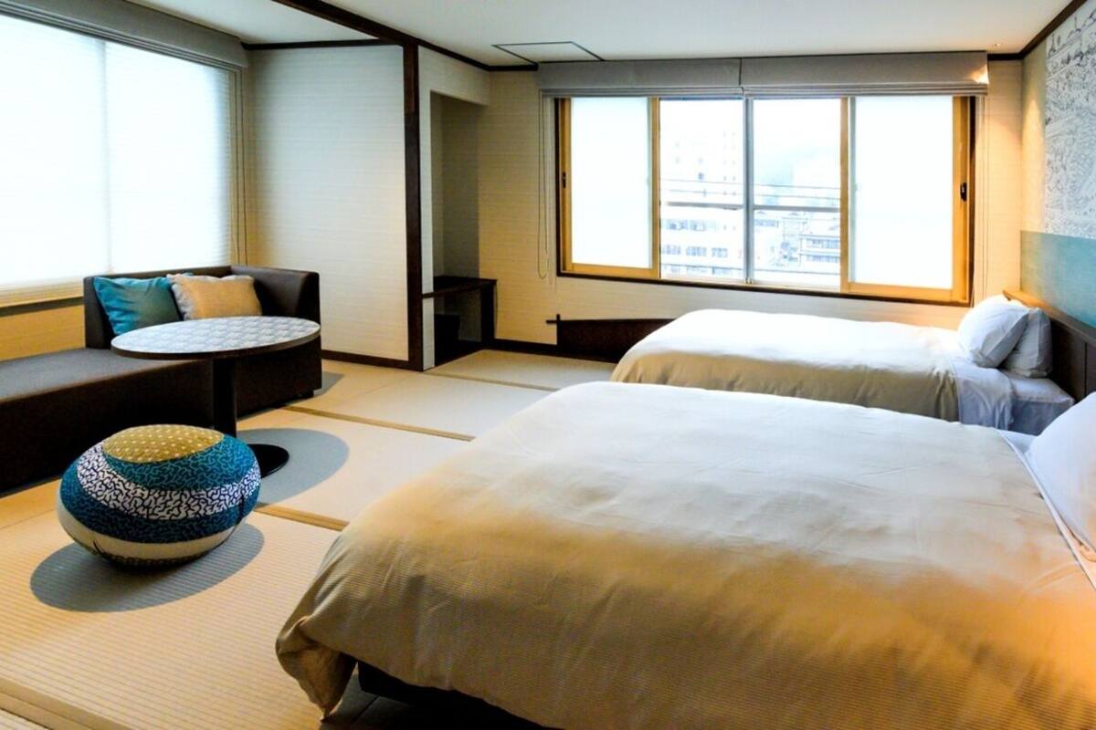 A hotel room with a bed, a sofa, a small round table, and a decorative bowl.