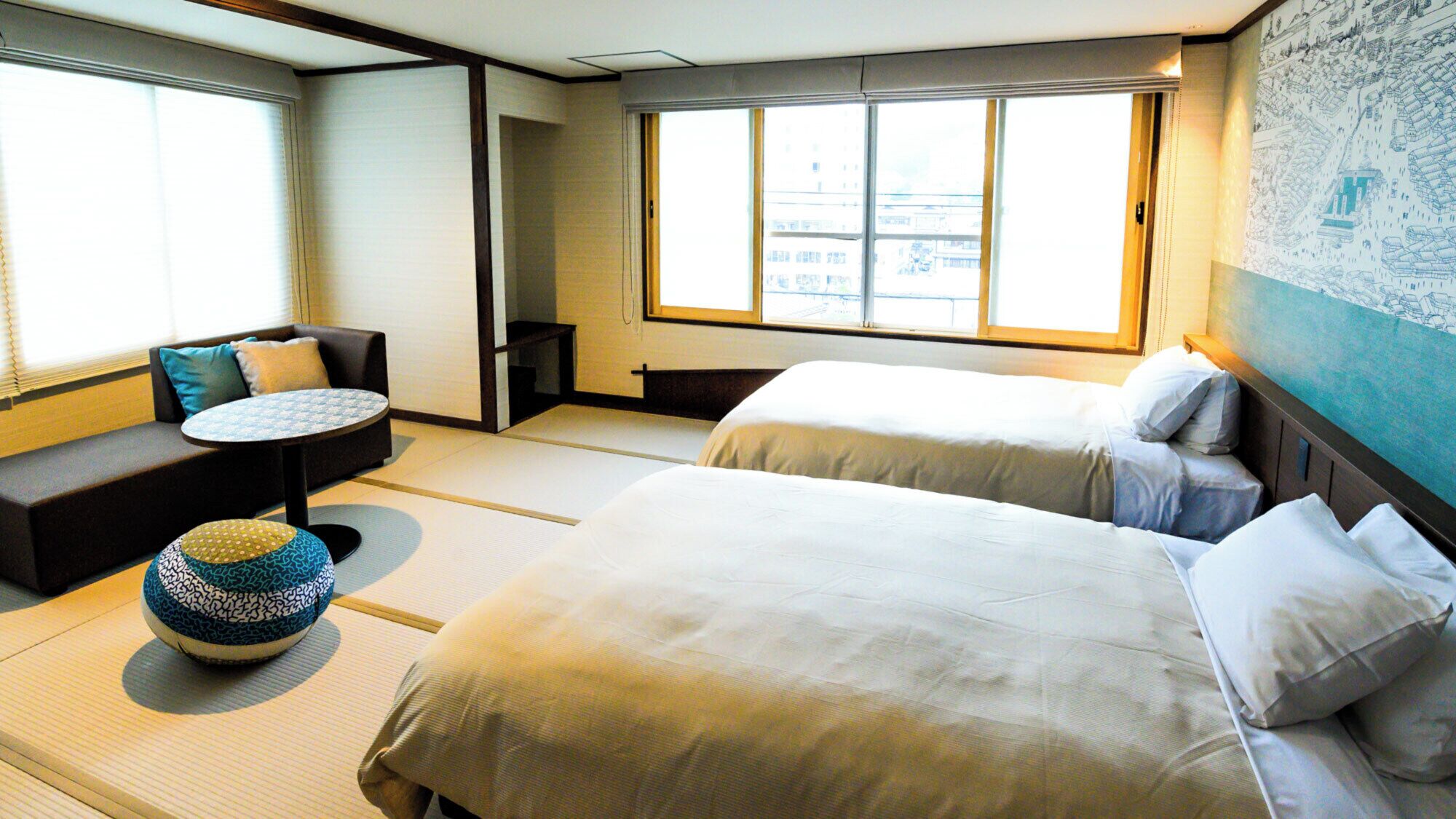 A hotel room with two beds, a sofa, a small table, and a tatami mat.