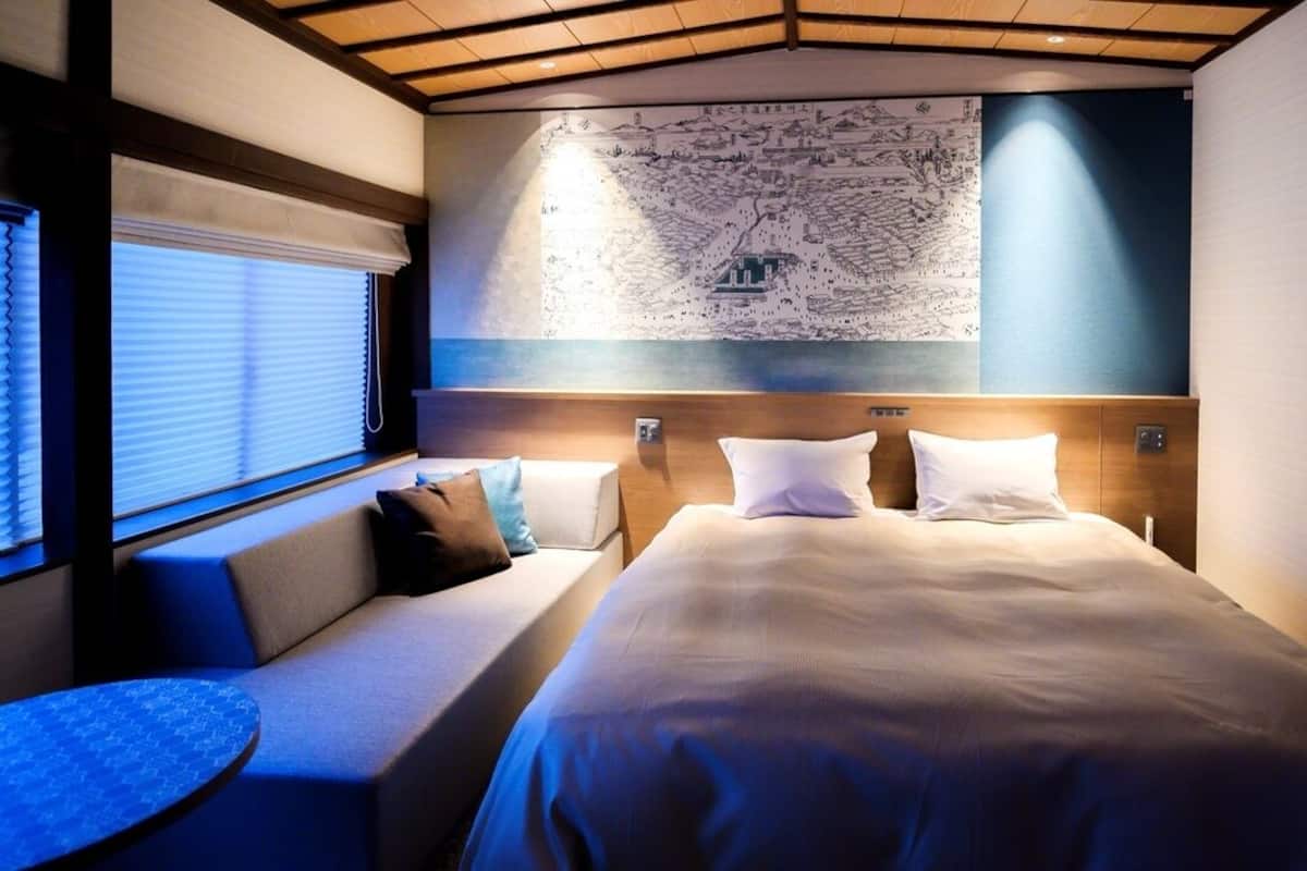 A bedroom with a large bed, two bedside tables, a sofa, and a map on the wall.
