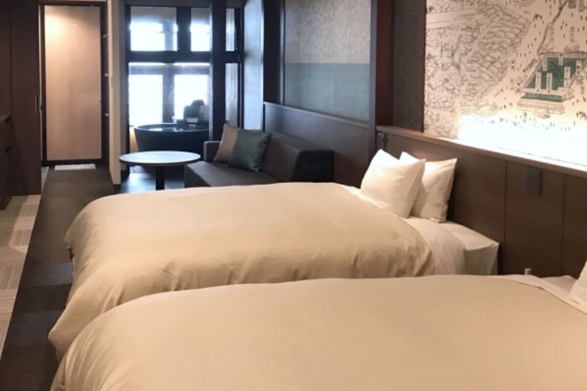 A hotel room with two beds, a sofa, a small table, and a map on the wall.