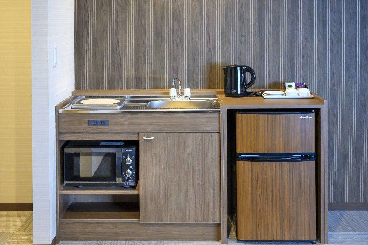 A compact kitchenette with a microwave, sink, and refrigerator.