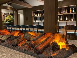 A bar area with a central fire feature, seating, and shelves of bottles. - Kusatsu Onsen Gensen Ichinoyu (Kusatsu)