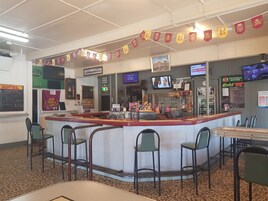 Un restaurante con mostrador, taburetes de bar y una pantalla de televisión.