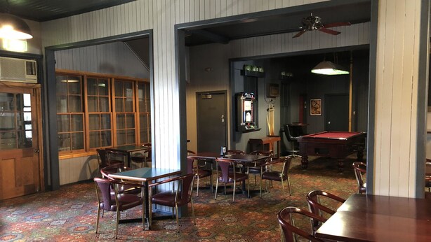 A room with a pool table, multiple tables and chairs, a patterned carpet, and a ceiling fan. - Kerwick Hotel (Redbank)