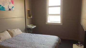 Una camera da letto con un letto, un comodino, una finestra e un'opera d'arte appesa al muro.