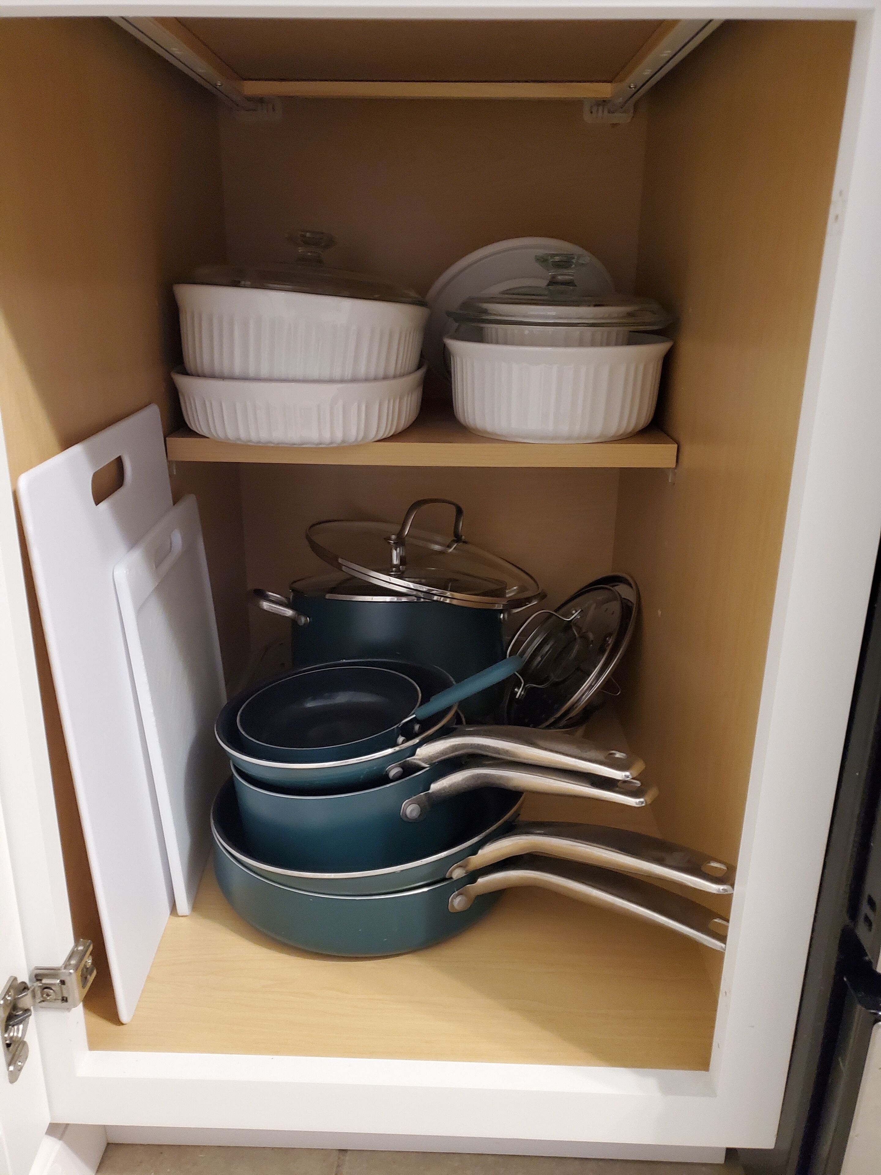 Un meuble de cuisine contenant des boîtes de rangement blanches et des ustensiles de cuisine bleus.