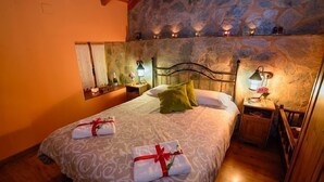 Una cama doble con una colcha estampada, dos almohadas y dos mesitas de noche con lámparas.