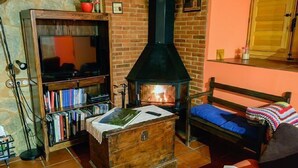 Una sala de estar acogedora con chimenea, estantería y un espacio de descanso confortable.