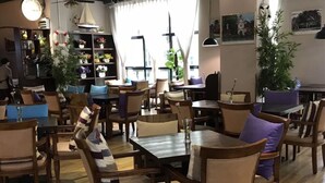 Un restaurant chaleureux, doté de meubles en bois et agrémenté de nombreuses plantes.