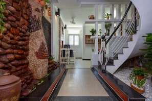 Un interior moderno con una pared de piedra, una escalera y plantas en macetas.