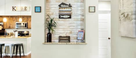 Zona de recepción con pared de madera rústica, un letrero de bienvenida, una decoración de pez y un banco.