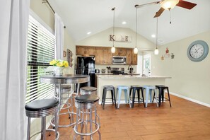 A kitchen with wooden cabinets, a central island, bar stools, and a clock on the wall.