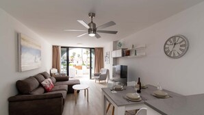 Ein modernes Wohnzimmer mit einer Couch, einem Esstisch und einem Fernseher.