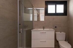 A modern bathroom with a glass shower enclosure, a white sink with a mirror above it, and a toilet. - Parque Santiago II 79 - Two Bed south facing (Playa de la Américas)