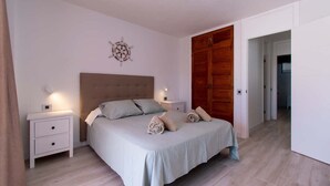 Ein Schlafzimmer mit einem Bett, zwei Nachttischen, einem Holzschrank und einer Wanddekoration.