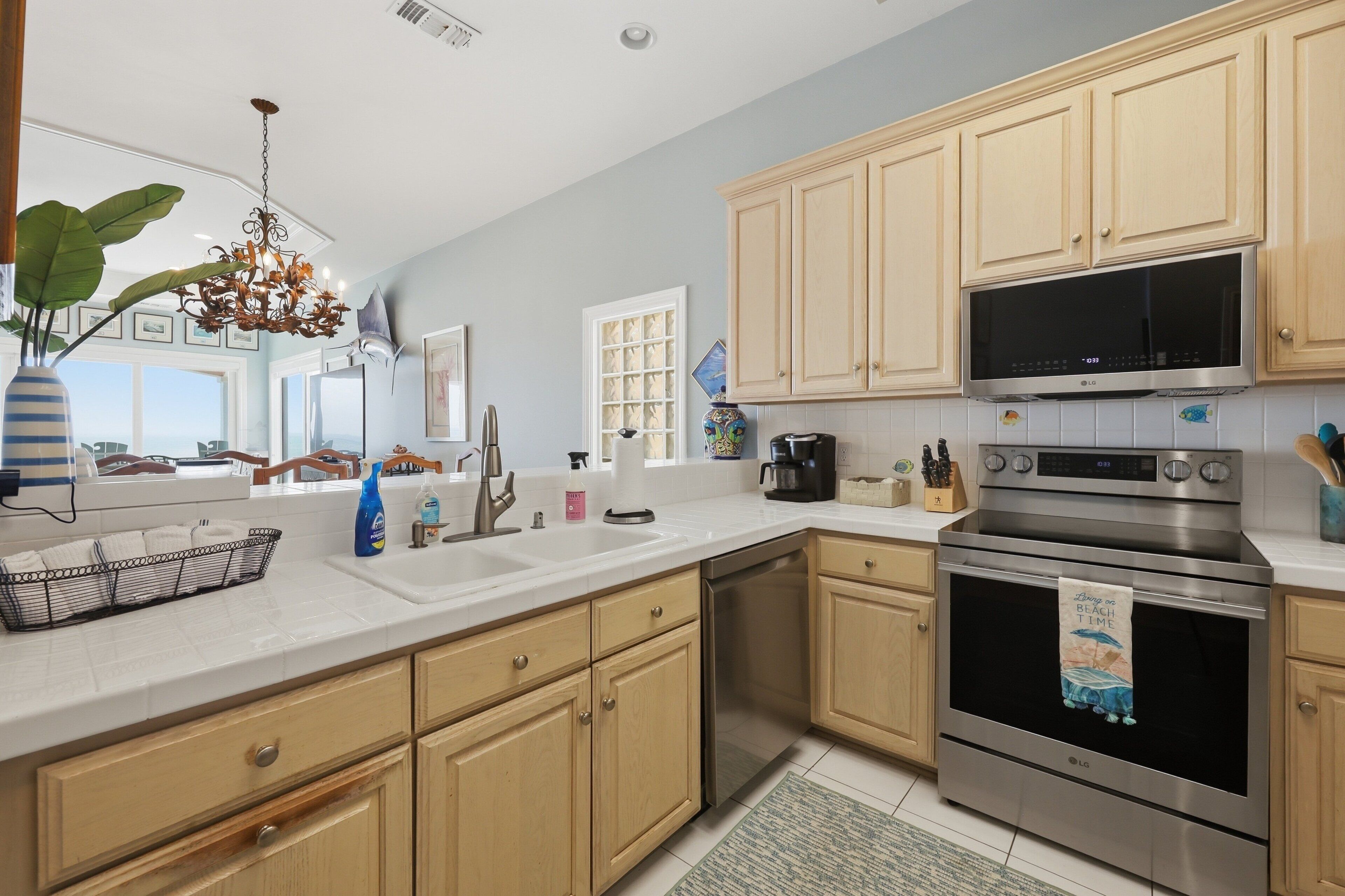 A kitchen with wooden cabinets, stainless steel appliances, a dishwasher, and a large window.