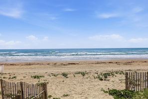 A beach with a wooden fence, sandy beach, and ocean waves.