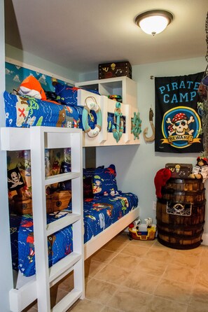 A bunk bed with a pirate-themed bedspread and a 'Pirate Camp Beware!' banner. - Pirate Theme 2nd floor1Bedroom+bunks  Highchair.Crib, Beach chairs, and Towels  (Panama City Beach)