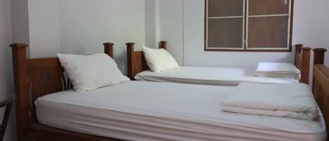 Una habitación con dos camas de madera, cada una con ropa blanca.