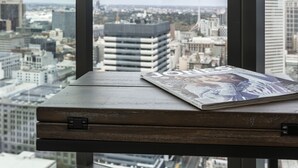A window with a view of a cityscape, a table with a magazine, and a city skyline. - Trendy Melbourne 2 Bedroom Apartment by BnB Pro (Melbourne)