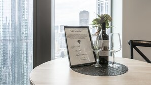 A welcome sign with WiFi details and a wine bottle on a table with a view of city buildings. - Trendy Melbourne 2 Bedroom Apartment by BnB Pro (Melbourne)