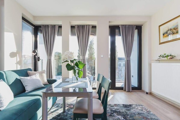 Relax in this stylish living room with a sofa, dining table, and large window overlooking the outdoors.