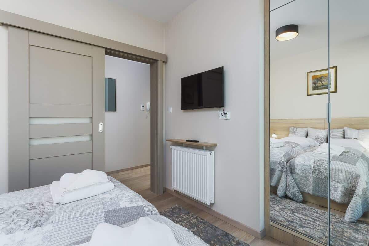Una habitación de hotel con cama, televisor, espejo y radiador.