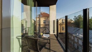 Een balkon met een glazen deur, rieten stoelen en een tafel met een drankje en een boek.