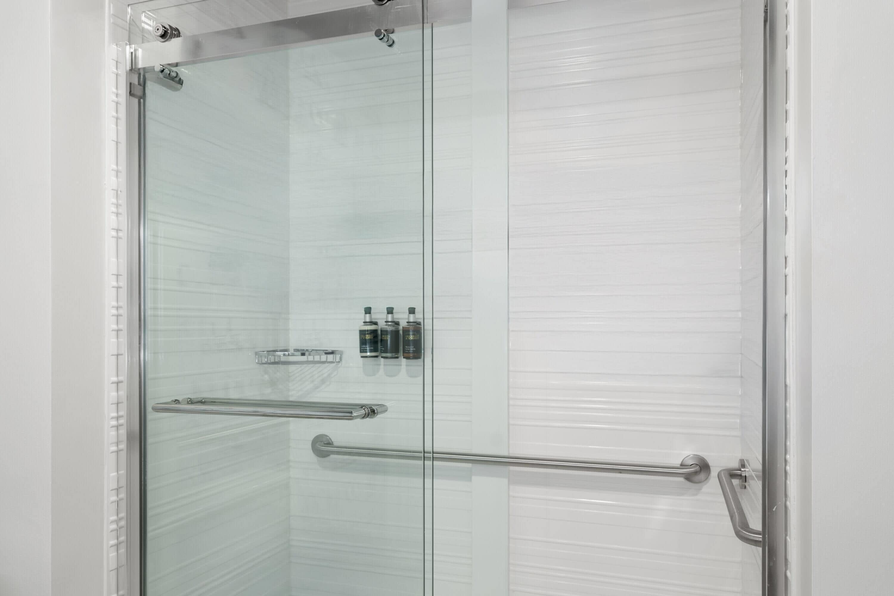 Een douche met glazen wanden, een metalen handgreep en een glazen deur.