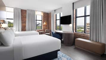 Une chambre d’hôtel avec un grand lit, un bureau, une chaise, un banc et un téléviseur.