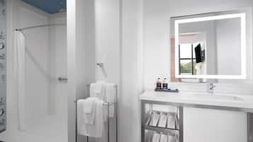 A modern bathroom with a walk-in shower, a white vanity with a large mirror, and a towel rack.
