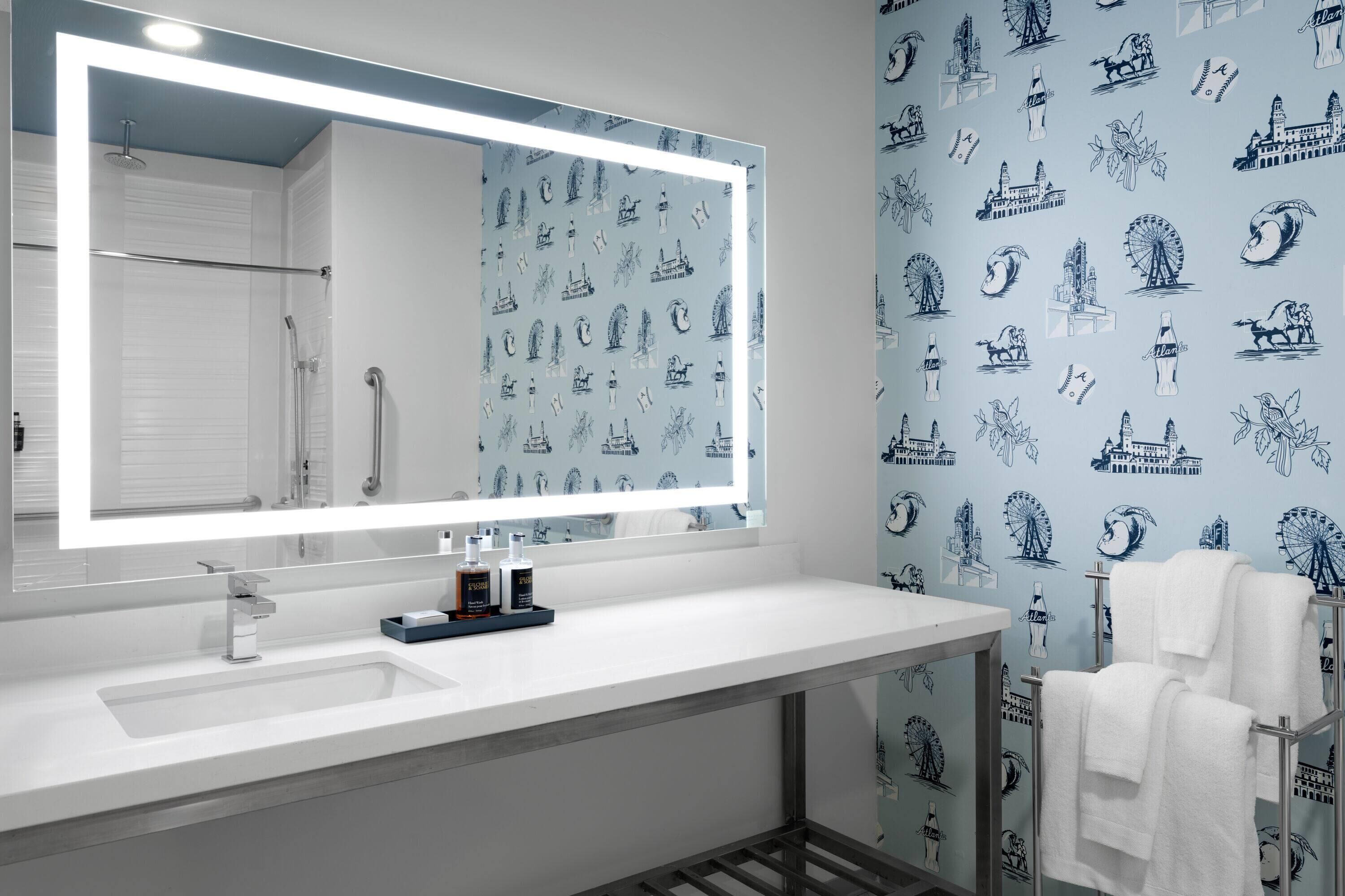 A bathroom with a large mirror, white sink, and a towel rack.