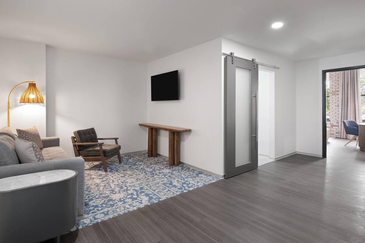 A modern living room with a sofa, a chair, a table, and a TV mounted on the wall.