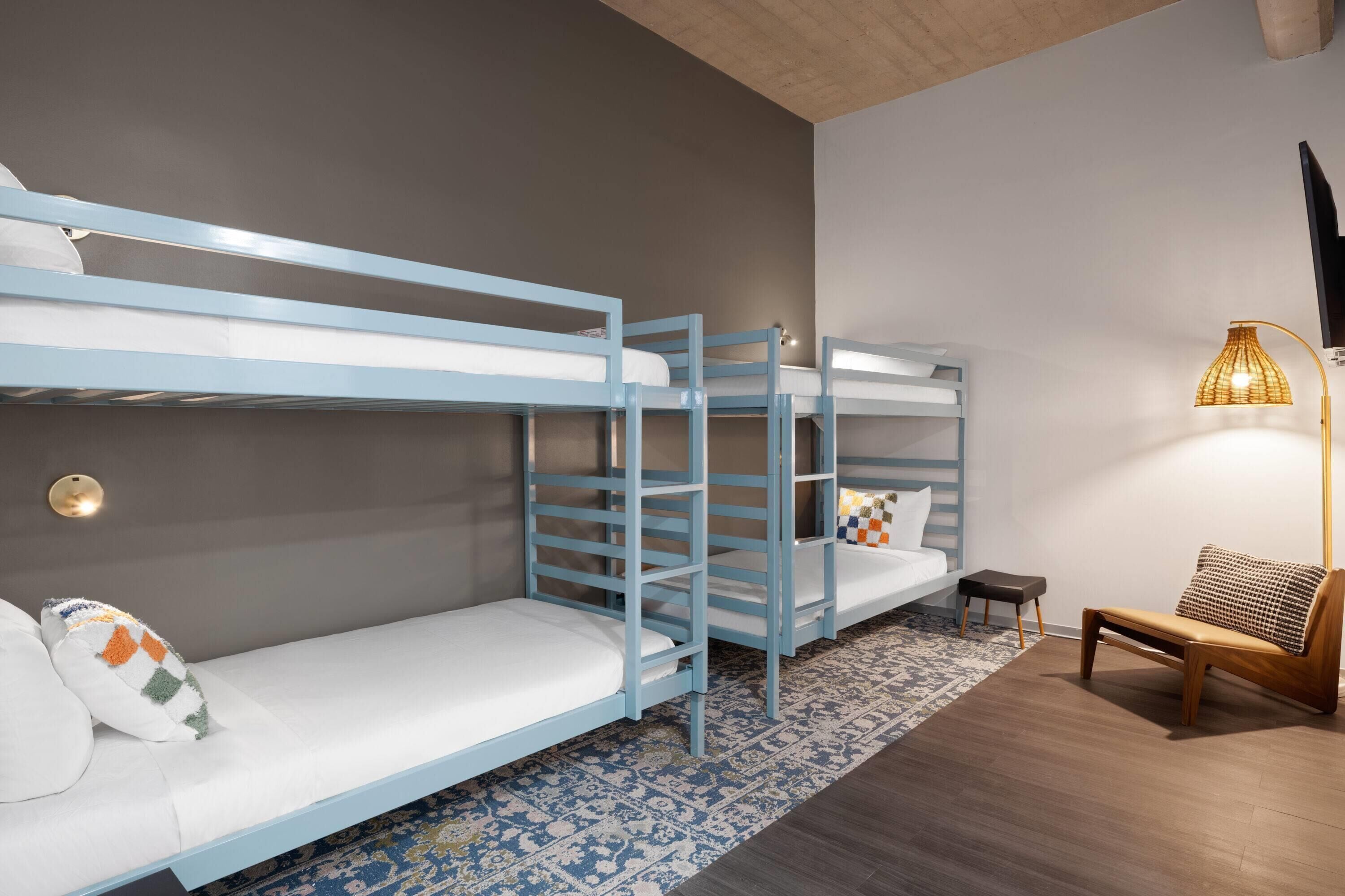 A bunk bed room with a small table and a lamp.