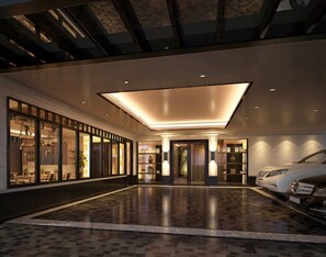 A spacious lobby with a polished floor, large windows, and a modern car parked inside.