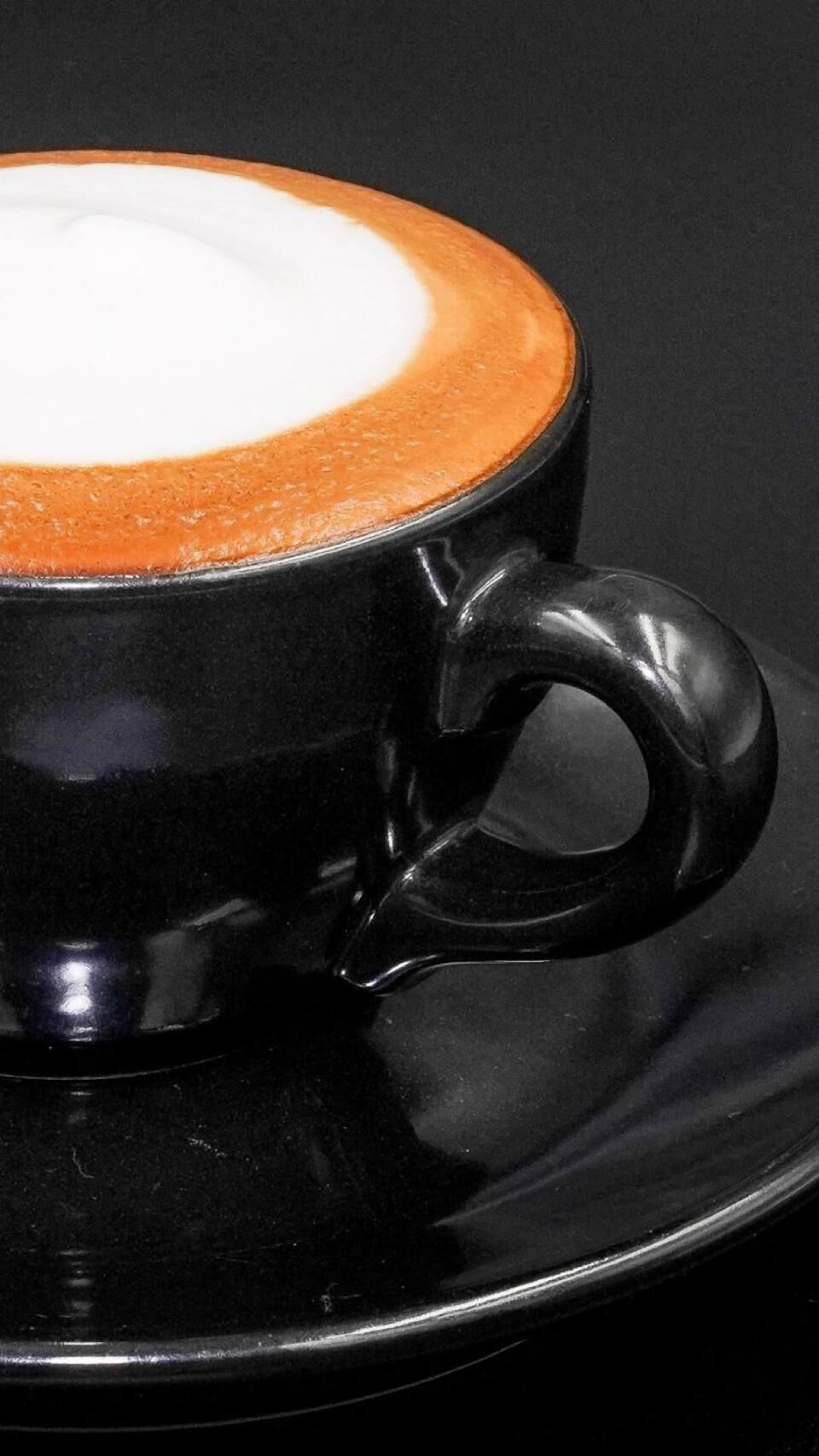 A black cup with a handle and a saucer.