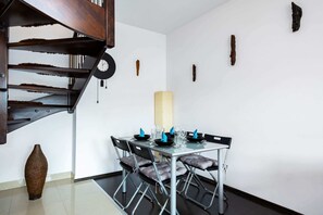 Een eetruimte met een spiltrap, een hoge vaas en een tafel gedekt voor vier personen.