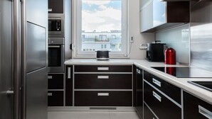 A modern kitchen with a built-in oven, a window with a view of buildings, and a stainless steel refrigerator.