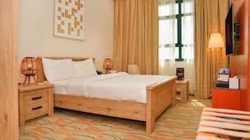 A hotel room with a wooden bed, two bedside tables, a TV, and a desk with a chair.