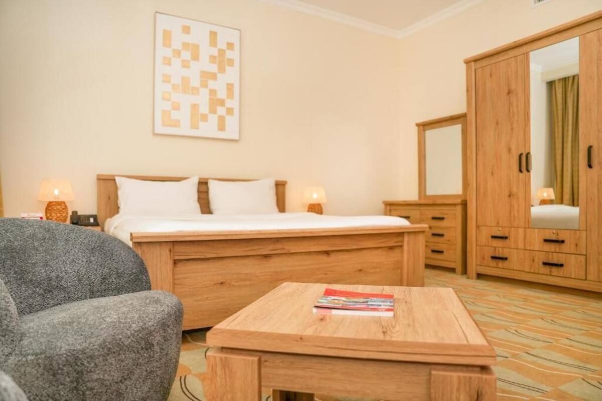 A bedroom with a bed, bedside tables, a wooden wardrobe, and a small table with books.